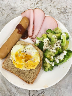A picture of Egg on toast with sausage, ham and broccoli salad.