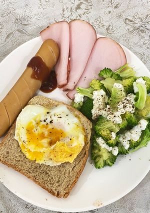 A picture of Egg on toast with sausage, ham and broccoli salad.