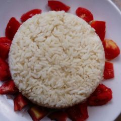 A picture of White rice and fresh tomatoes.