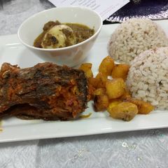 A picture of Ofada rice and sauce with fried plantain amd peppered fish.
