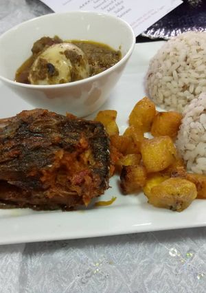 A picture of Ofada rice and sauce with fried plantain amd peppered fish.