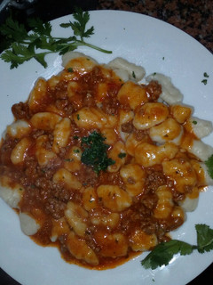 Una foto de Ñoquis con salsa bolognesa y cilantro