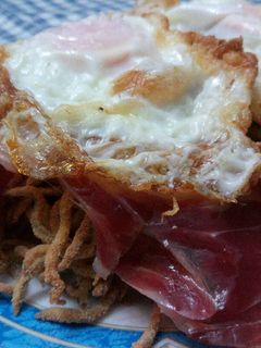 Una foto de Huevos rotos con jamón sobre chanquetes de pobre (gulas)
