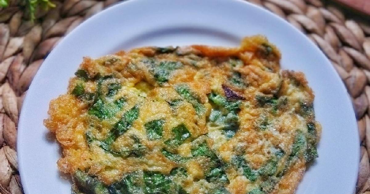 Sepiring sawi omelet hangat dengan warna keemasan, disajikan dengan irisan tomat cherry