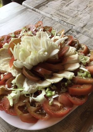 Une photo de Salade de tomates noires, mozzarella di buffala et oignons nouveaux