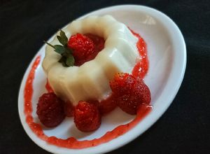 Una foto de Panna cotta de coco con cuolis de fresa