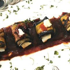 A picture of Cheesey brinjal roll in tomato sauce.