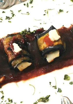 A picture of Cheesey brinjal roll in tomato sauce.