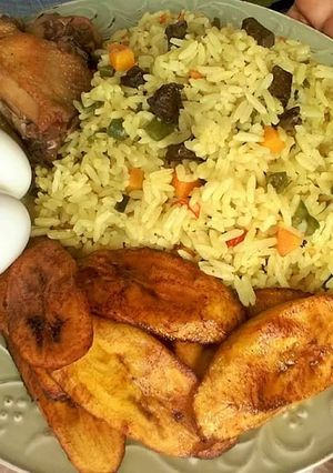 A picture of Fried rice with fried plantain,boiled egg and chicken.