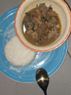 A picture of Goat meat and assorted meat pepper soup with white rice.