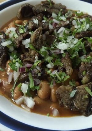 Una foto de Frijoles con arrachera, cilantro y cebolla morada