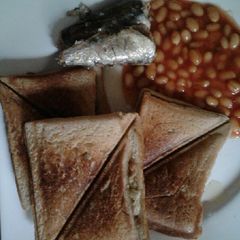 A picture of Scrambled eggs in a Toast with sardine and baked beans.