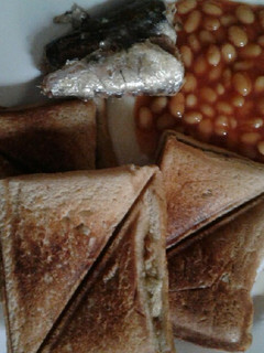 A picture of Scrambled eggs in a Toast with sardine and baked beans.