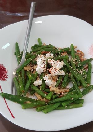A picture of French beans tossed with nuts and feta cheese salad.
