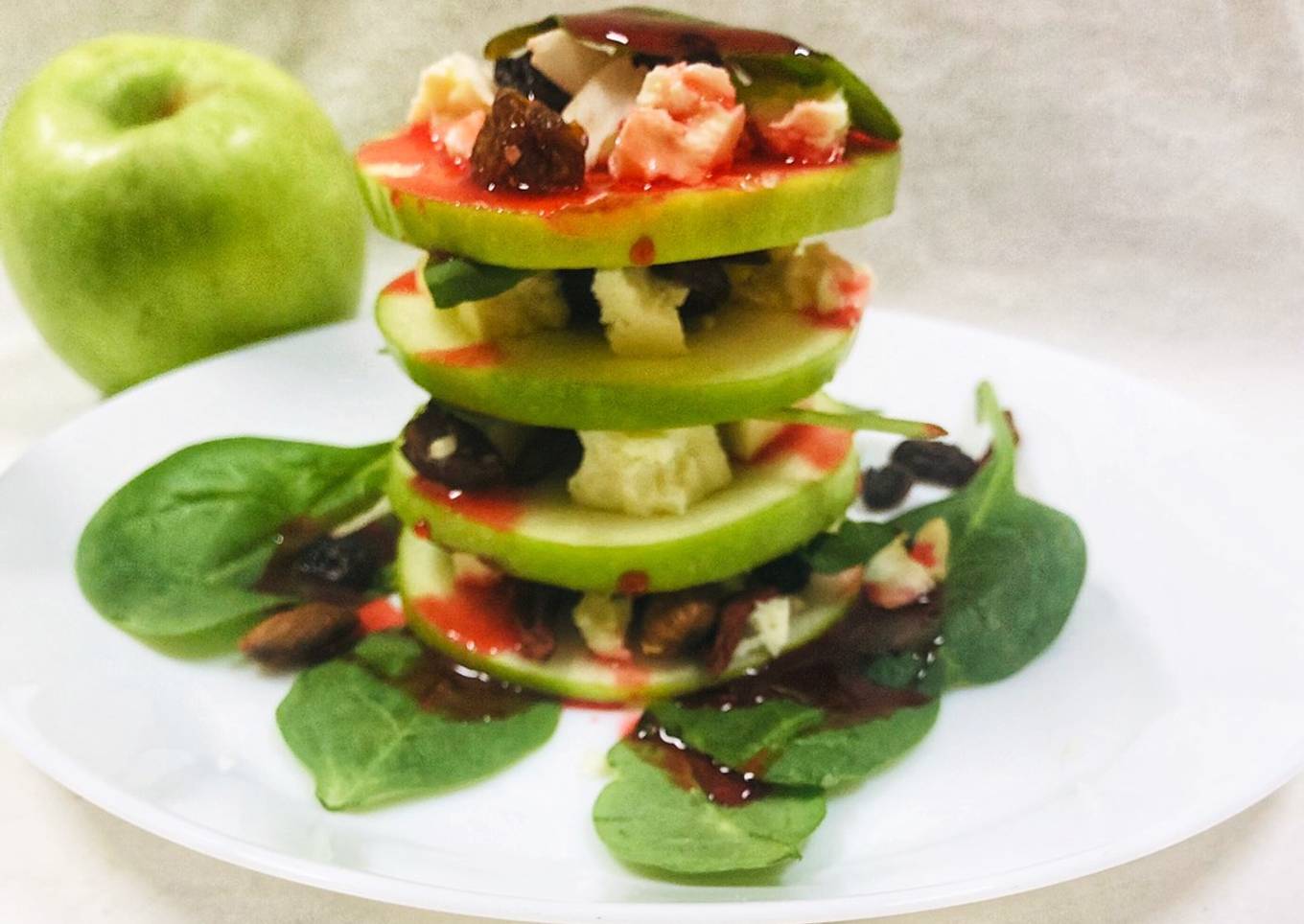 Green apple salad with cheese, dried fruits and strawberry sauce