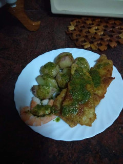 Una foto de Merluza empanada con papas arrugás, langostinos y mojo verde