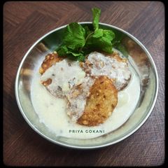 A picture of Sabudana Vada dipped in Dahi Jeera Tadka Kadhi.
