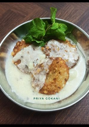 A picture of Sabudana Vada dipped in Dahi Jeera Tadka Kadhi.