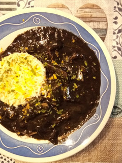 Una foto de Calamares de potera en salsa de verduras y tinta con arroz blanco y escamas de naranja
