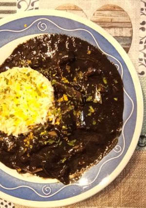 Una foto de Calamares de potera en salsa de verduras y tinta con arroz blanco y escamas de naranja