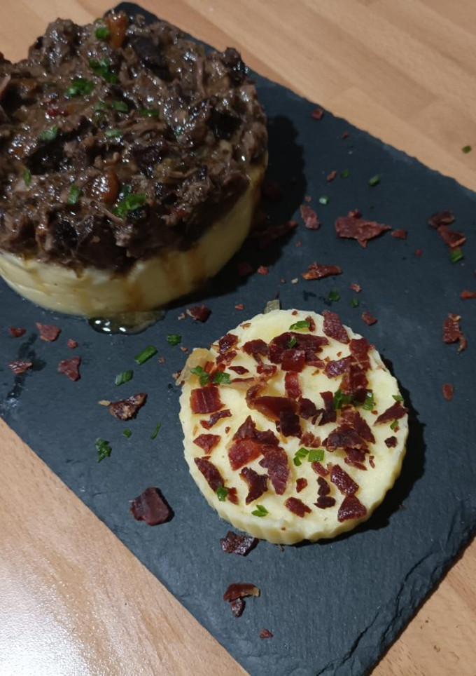 Una foto de Timbal de rabo de toro y puré de patatas con crujiente de jamón