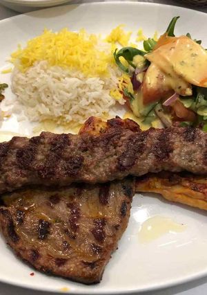 A picture of Rice with grilled meat with stew and salad.