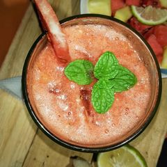 A picture of Watermelon, pineapple smoothie with a touch of fresh mint leaves.