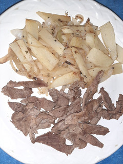 Una foto de Bistec y guarnición de papa y cebolla