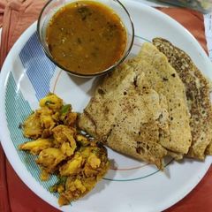 A picture of Bajra ki roti with urad dal and aloo sabzi.