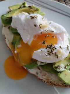 A picture of Avocado toast con formaggio spalmabile, uovo in camicia e mandorle a scaglie.