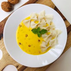A picture of Fresh farfalle(bow-tie/butterfly) pasta with roasted yellow pepper alfredo sauce.