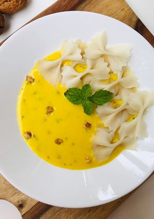A picture of Fresh farfalle(bow-tie/butterfly) pasta with roasted yellow pepper alfredo sauce.