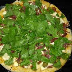 Una foto de Pizza de rúcula y jamón crudo