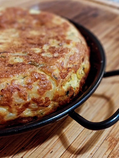 Una foto de Tortilla de patatas, bacalao, cebolla y pimiento verde
