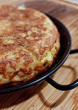 Una foto de Tortilla de patatas, bacalao, cebolla y pimiento verde