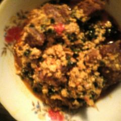 A picture of Egwusi soup garnished with ugu leaves.