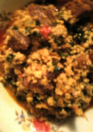 A picture of Egwusi soup garnished with ugu leaves.