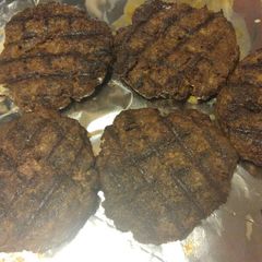 A picture of Juicy venison burgers in a skillet.