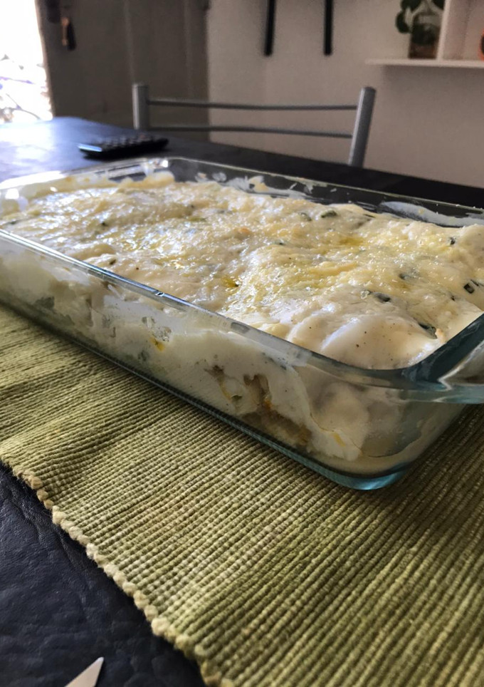 Una foto de Niños envueltos en repollo de carne con salsa blanca al horno