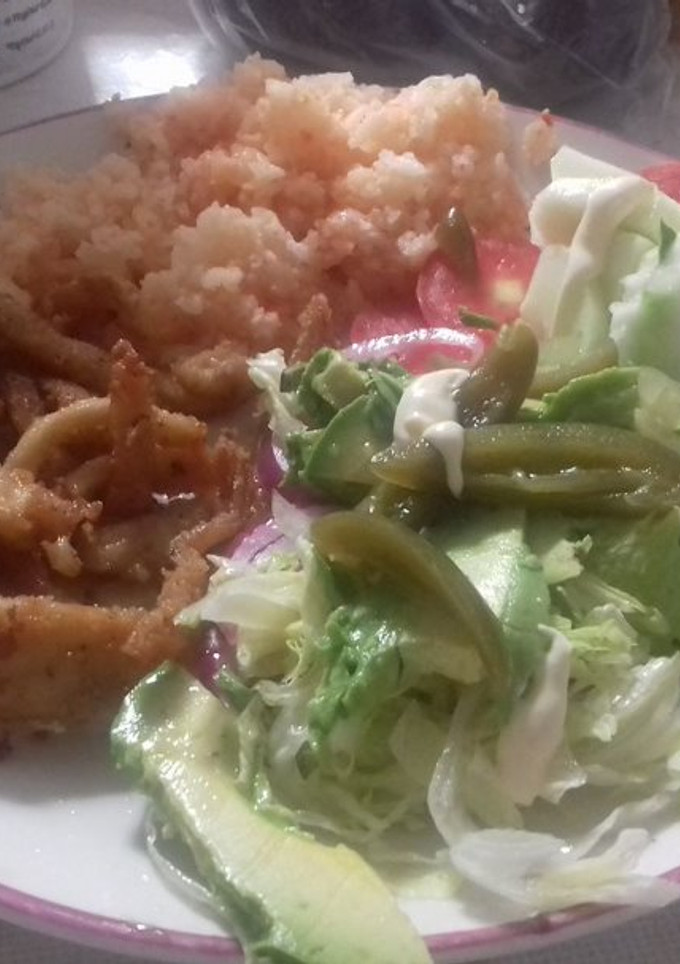 Una foto de Chicharrón de pescado con mezquite, ensalada de pepino y aguacate acompañados de arroz rojo mexicano