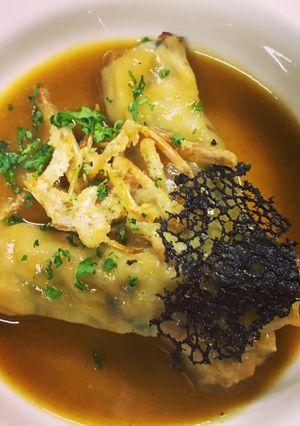 Una foto de Canelón de pasta wonton rellena de gambas y shiitake con fondo del jugo de la gamba