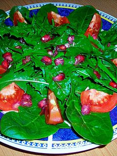 Una foto de Ensalada de espinaca, diente de león, granada y tomates