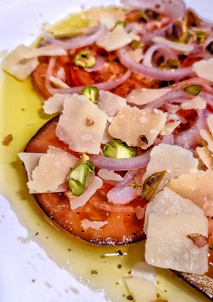 Una foto de Carpaccio de tomate con cebolla morada encurtida