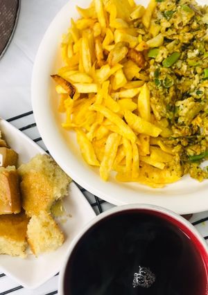 A picture of Chips with scrambled egg served with hot tea.
