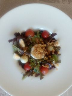 Una foto de Ensalada de brotes con huevo de codorniz y queso de cabra, y cherry y vinagreta de cítrico
