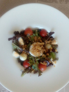Una foto de Ensalada de brotes con huevo de codorniz y queso de cabra, y cherry y vinagreta de cítrico