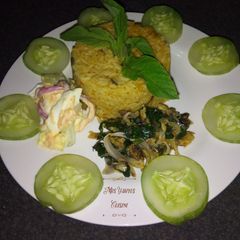 A picture of Jollof rice with dried fish sauce and coleslaw.