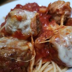 A picture of Mozzarella pork meatballs over spaghetti.