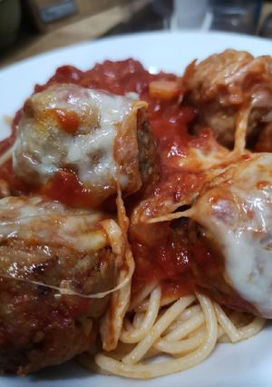 A picture of Mozzarella pork meatballs over spaghetti.