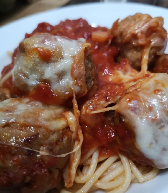 A picture of Mozzarella pork meatballs over spaghetti.